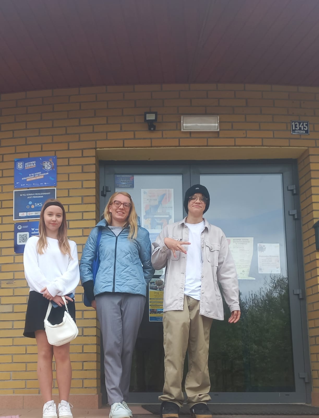 GMINNY KONKURS WIEDZY O KRAJACH ANGLOJĘZYCZNYCH uczestnicy konkursu wiedzy o krajach anglojęzycznych z opiekunem przed budynkiem szkoły w czasie prezentacji plakatu